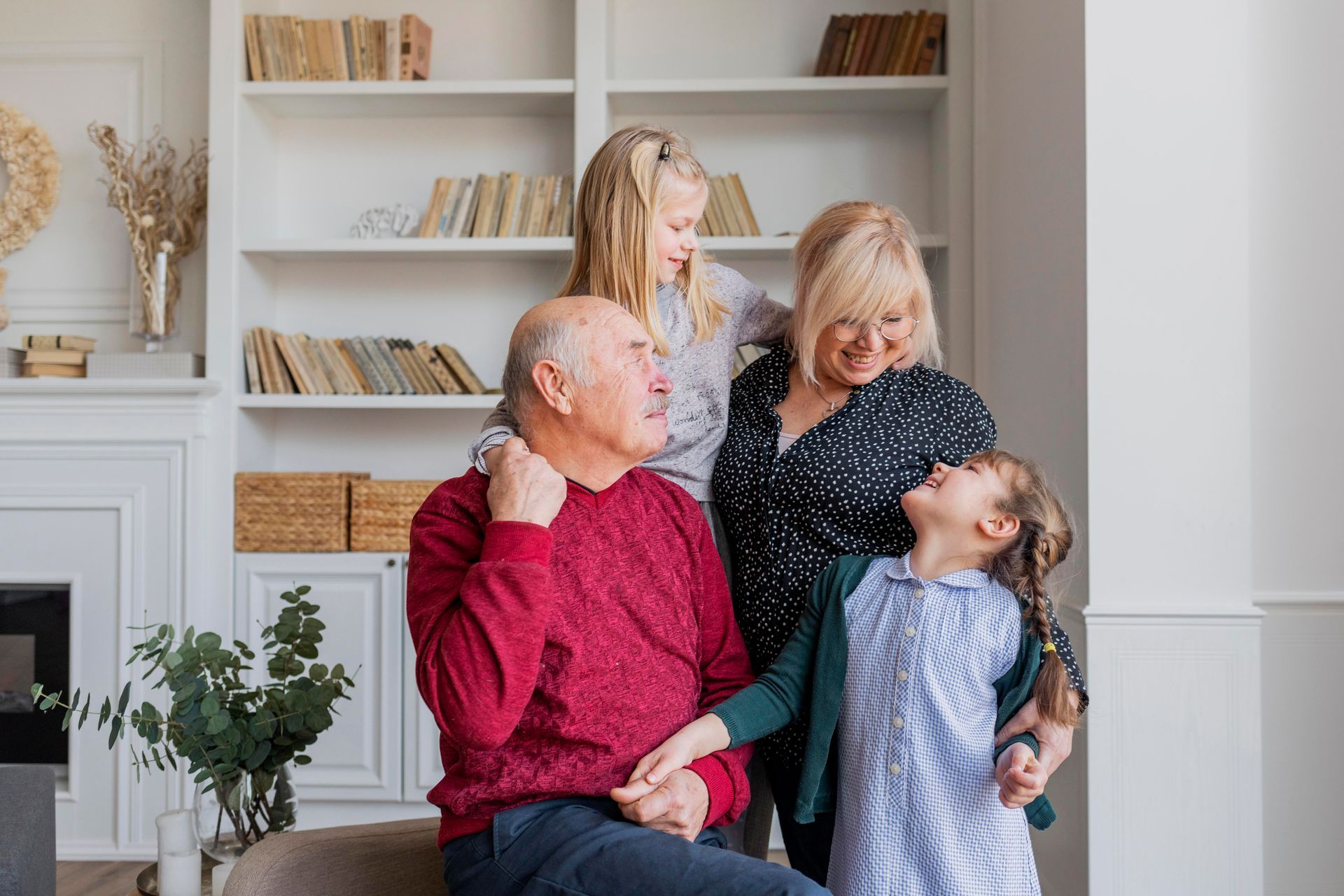 Family gathered in a bright living room, smiling and embracing near a white bookshelf