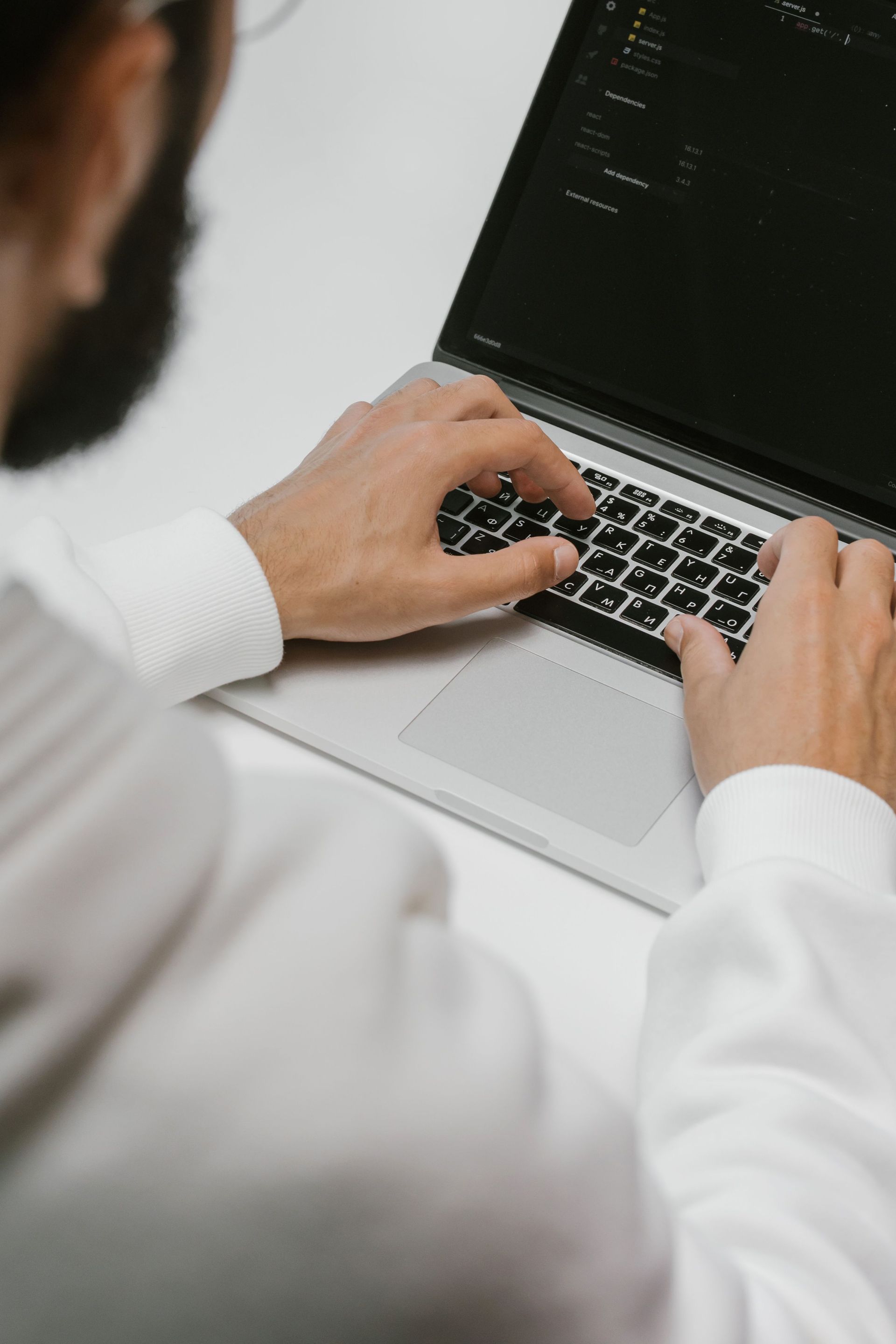 Person typing on a laptop with a dark screen in a bright indoor setting
