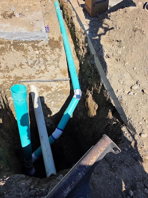 Black pipes laid in a dirt trench at a construction site