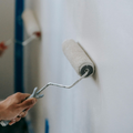 Hand rolling white paint onto a wall with a paint roller