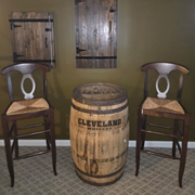 Two wooden chairs flanking a rustic Cleveland whiskey barrel in a dim room