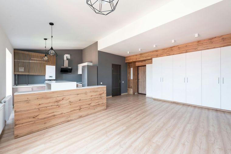 Modern open-plan kitchen with wood island, white cabinets, and light wood flooring