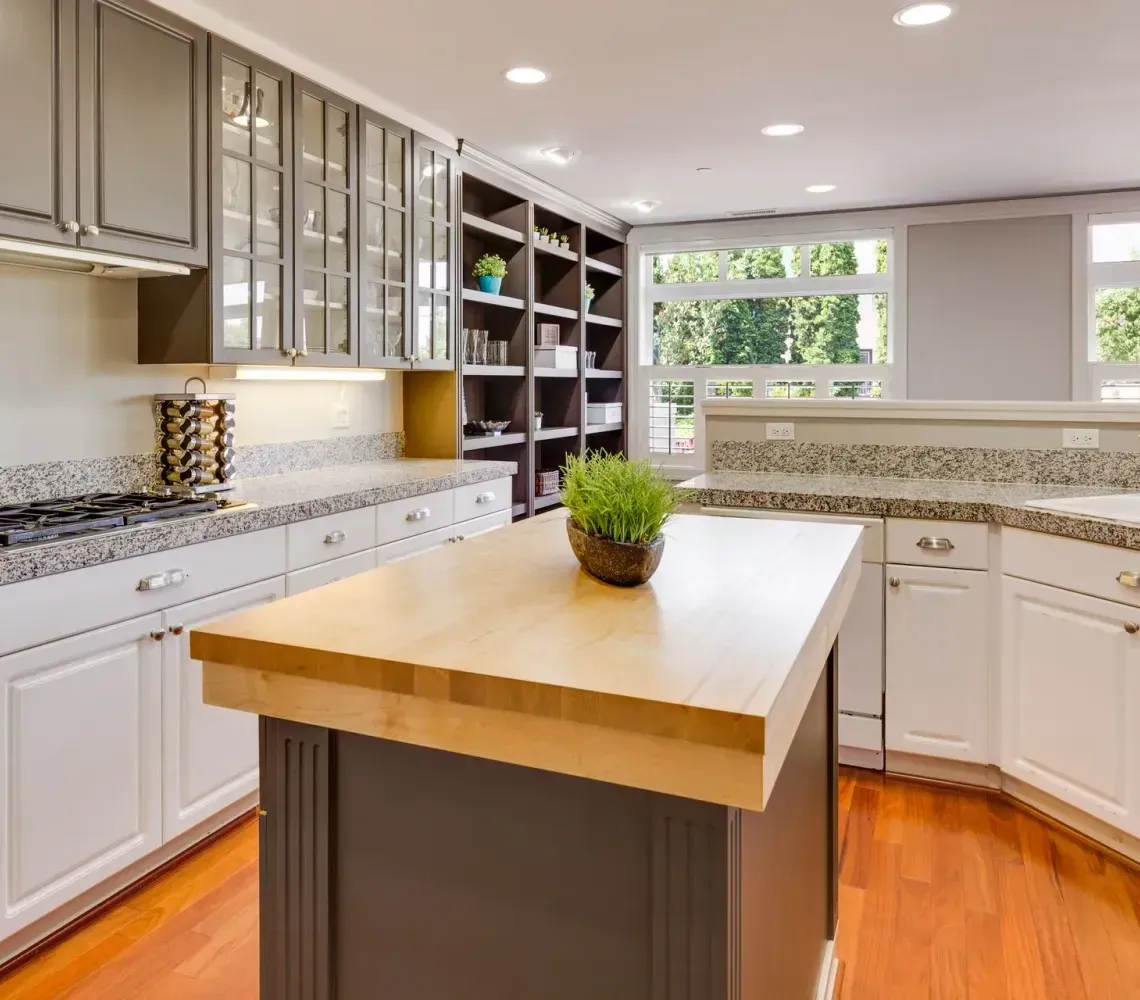Bright modern kitchen with white cabinets, granite countertops, and a wooden island centerpiece