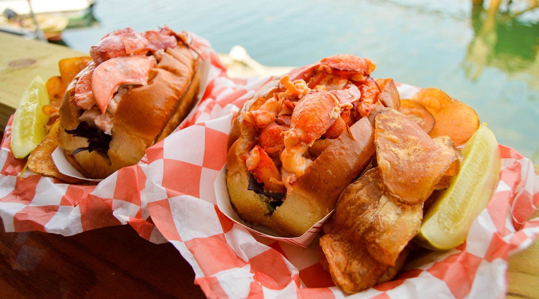 Two delicious Lobster rolls with a lemon wedge.