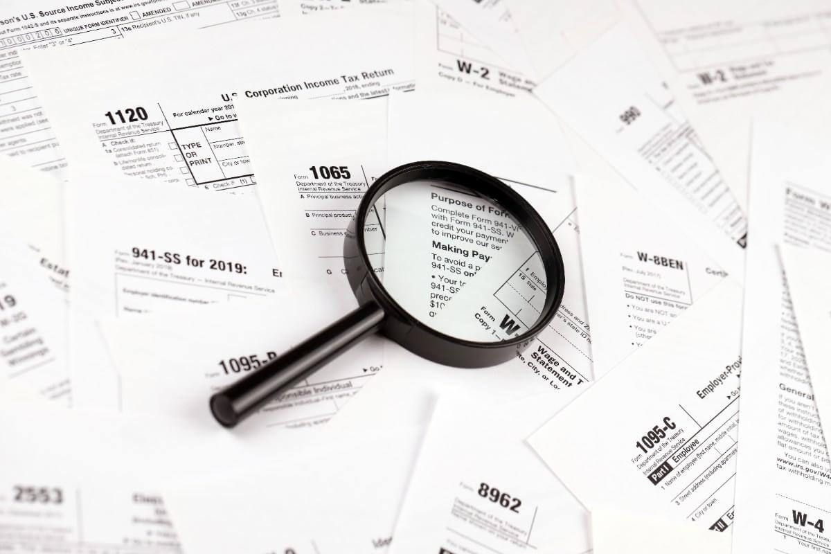 Magnifying glass over scattered invoices and receipts on a white background