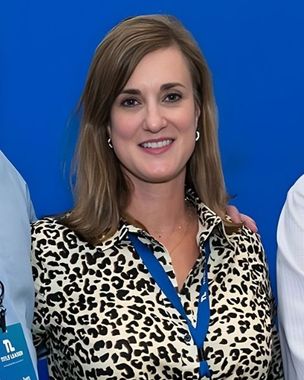 Smiling woman in leopard-print blouse and blue lanyard against a blue background