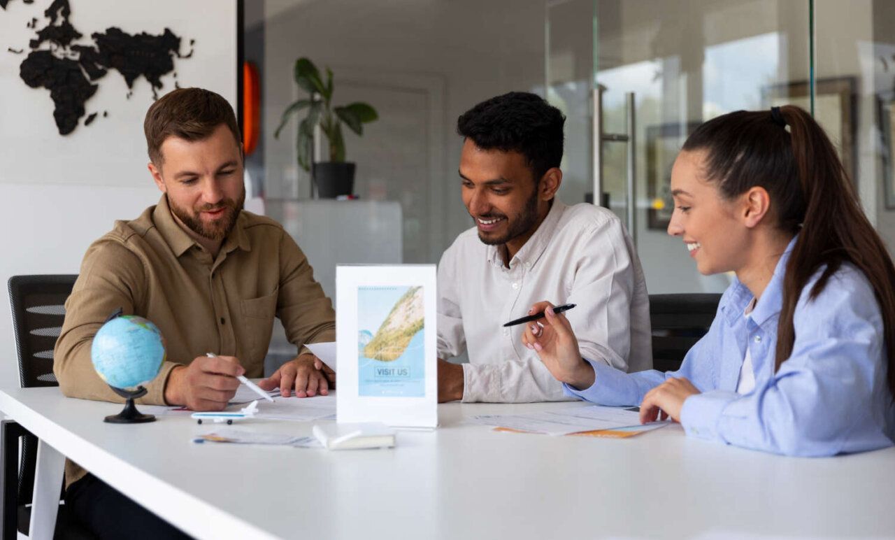 Three coworkers discussing charts at a white table in a bright office