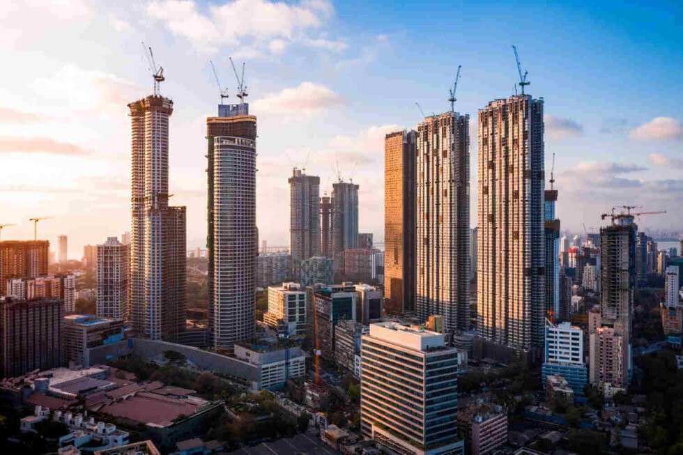 City skyline with tall high-rise towers under construction at sunset.