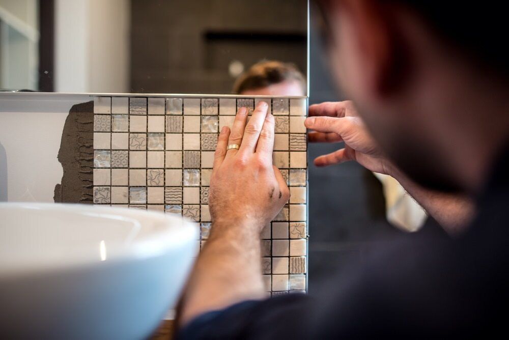 A Man is Installing a Mosaic Tile in a Bathroom — ASpect Wall & Floor Tiling in Charmhaven, NSW