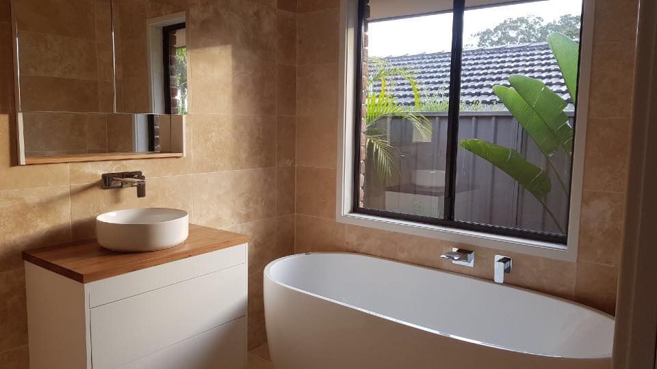 A Bathroom With a Tub , Sink , Mirror and Window — ASpect Wall & Floor Tiling in Tuncurry, NSW