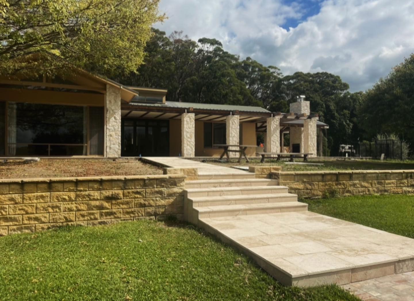 A House With Stairs Leading Up to It is Surrounded by Grass and Trees — ASpect Wall & Floor Tiling in Tuncurry, NSW