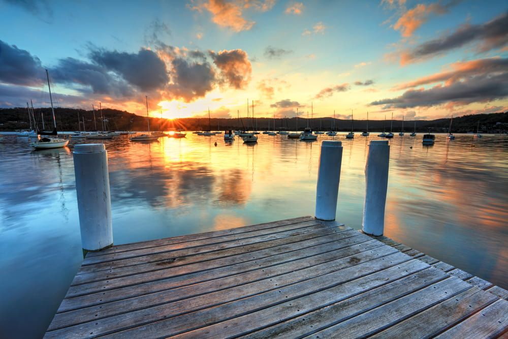 A Wooden Dock Overlooking a Body of Water at Sunset — ASpect Wall & Floor Tiling in Gosford, NSW