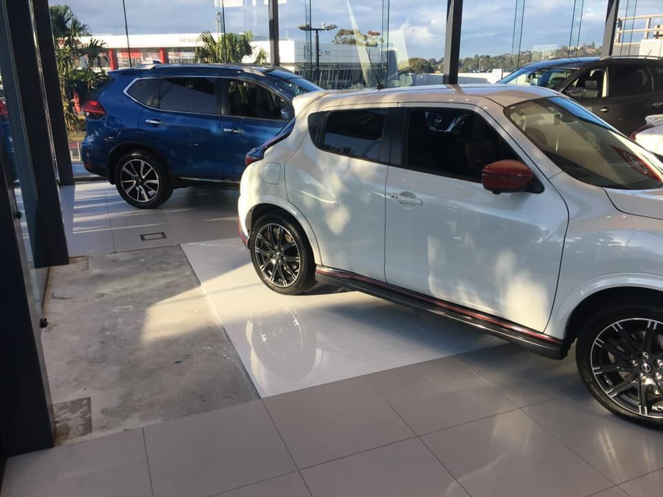 A White Car is Parked Next to a Blue SUV in a Showroom — ASpect Wall & Floor Tiling in Tuncurry, NSW