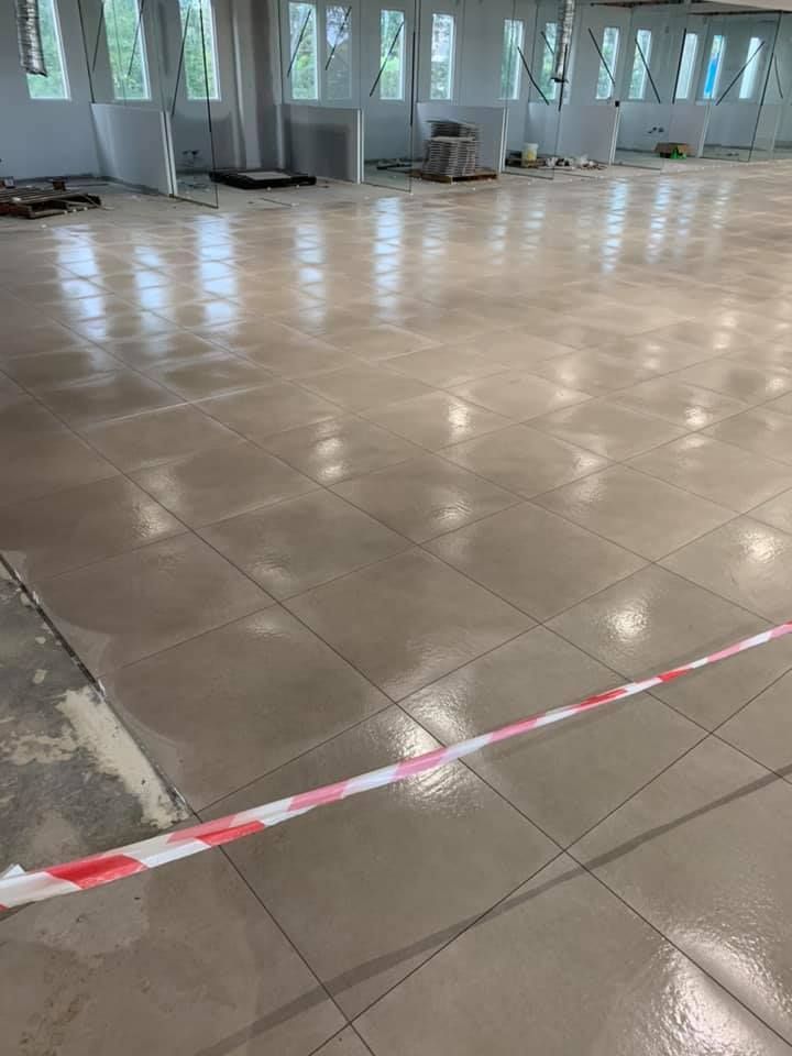 A Large Empty Room With a Tiled Floor and a Red and White Tape — ASpect Wall & Floor Tiling in Charmhaven, NSW