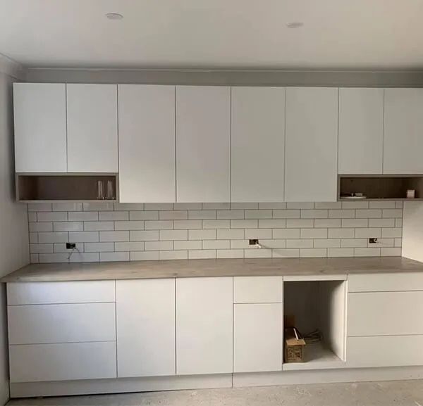 A Kitchen With White Cabinets and a Brick Wall — ASpect Wall & Floor Tiling in Tuncurry, NSW