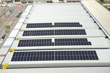 Pannelli solari installati in file sul tetto di un grande edificio industriale.