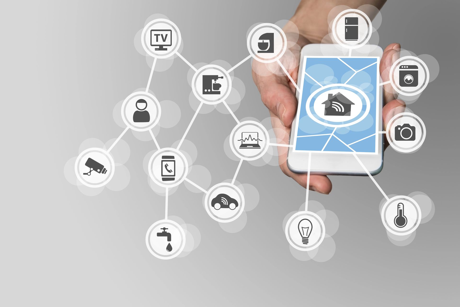 Una mano che tiene uno smartphone con icone di domotica connesse in uno sfondo di rete digitale