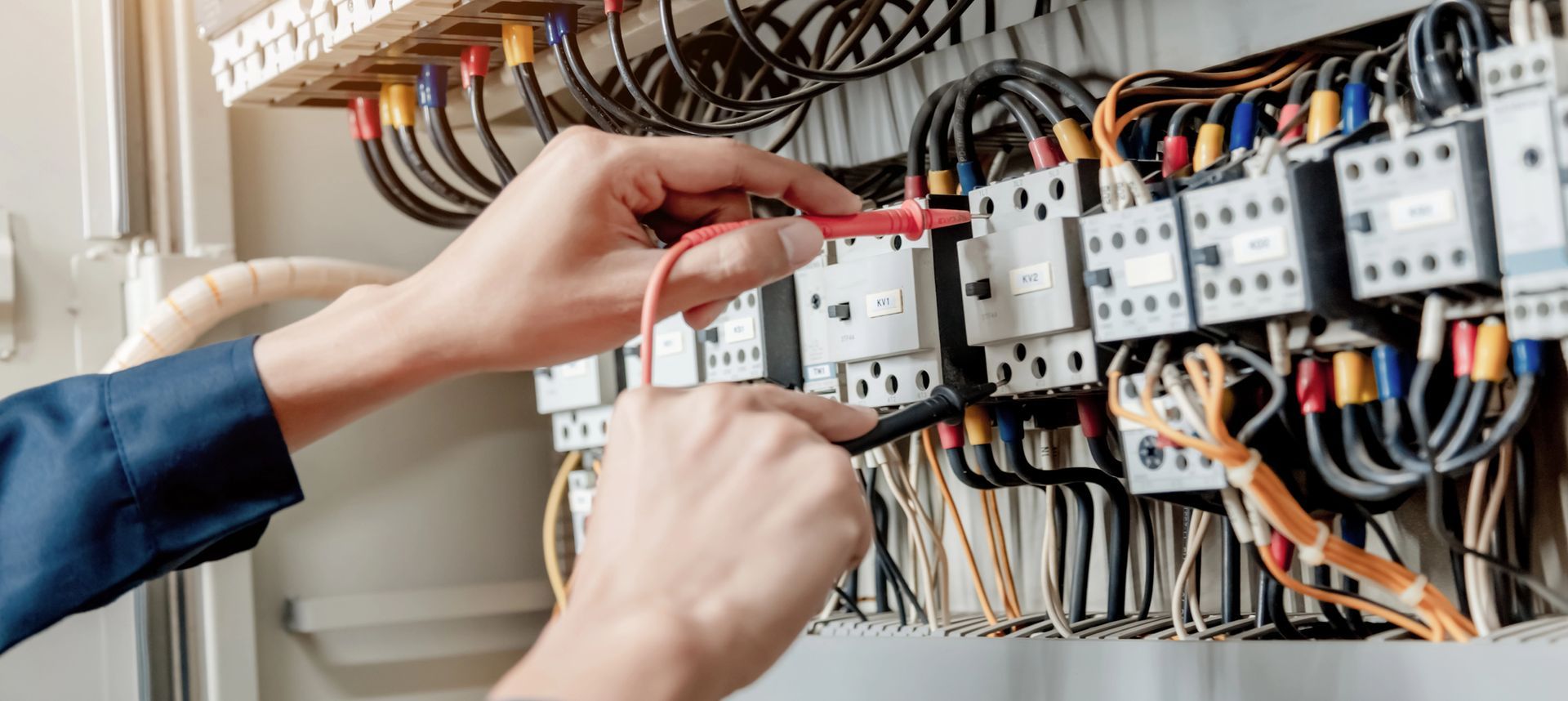 Mani che regolano il cablaggio elettrico in un quadro di controllo aperto con relè e cavi