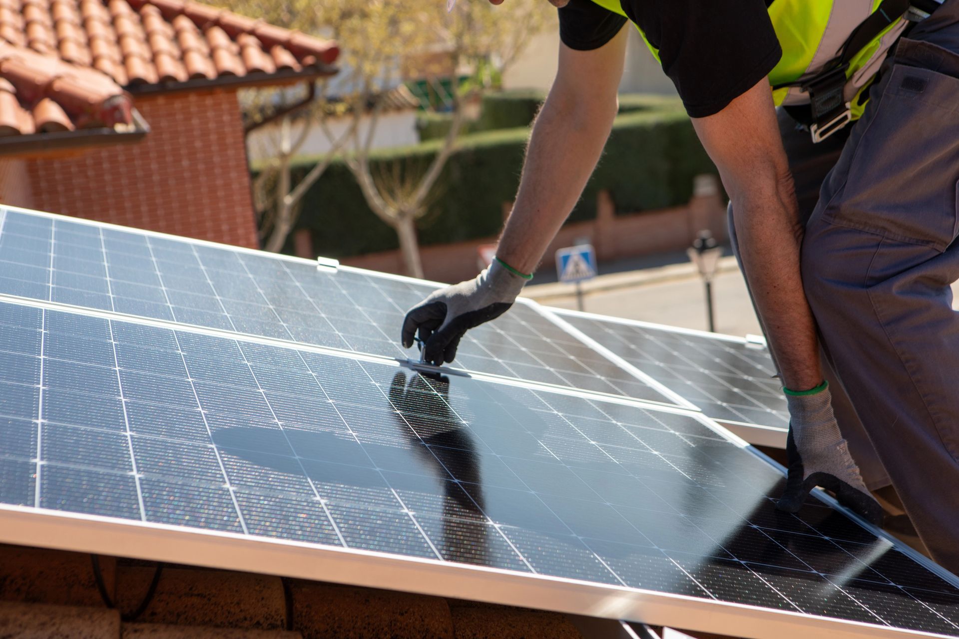 Un operaio pulisce un pannello solare sul tetto con un tergivetro in una giornata di sole.