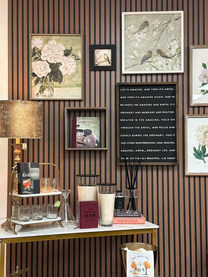 Wall displaying frames, wall art, candles, signs, and decorative items in a store.