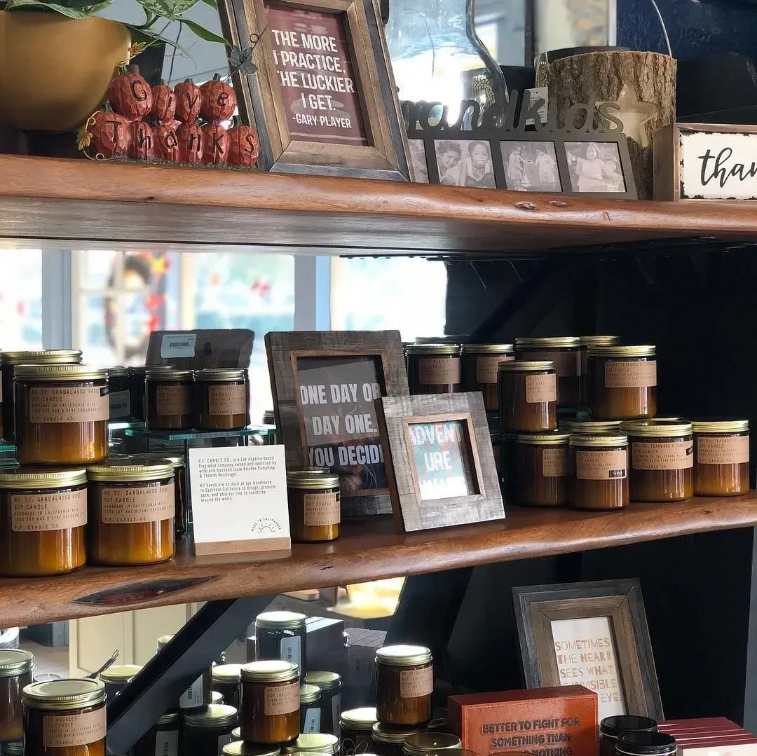 Wall displaying frames, wall art, candles, signs, and decorative items in a store.