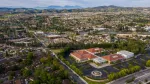Aerial view of a suburban neighborhood with a school campus featuring red-roofed buildings and a roundabout