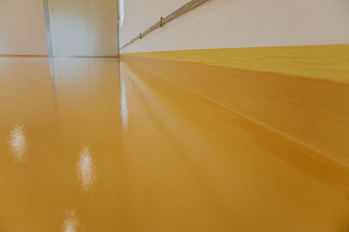 Empty hallway with glossy yellow floor and white walls, viewed from a low angle