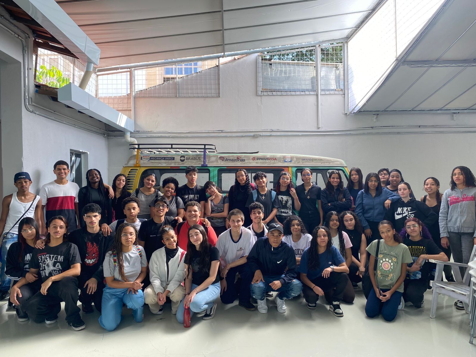 Um grande grupo posando para uma foto em um salão interno bem iluminado