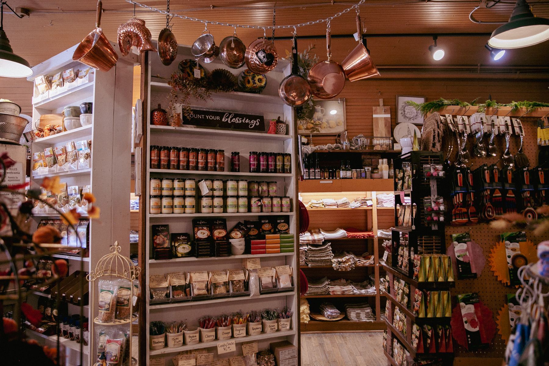 Cozy shop aisle with shelves of jars, snacks, and hanging gifts under warm string lights