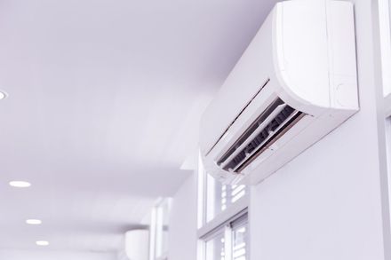 White wall-mounted air conditioner in a bright, white room.