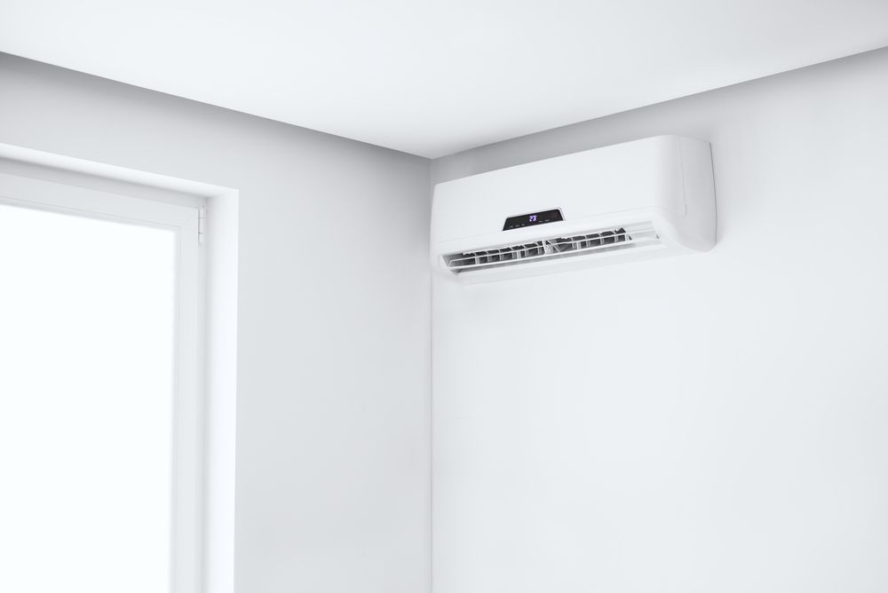 White Air Conditioner Mounted on a White Wall in a Corner of a Room — RedJak Air Conditioning Services in Willawong, QLD