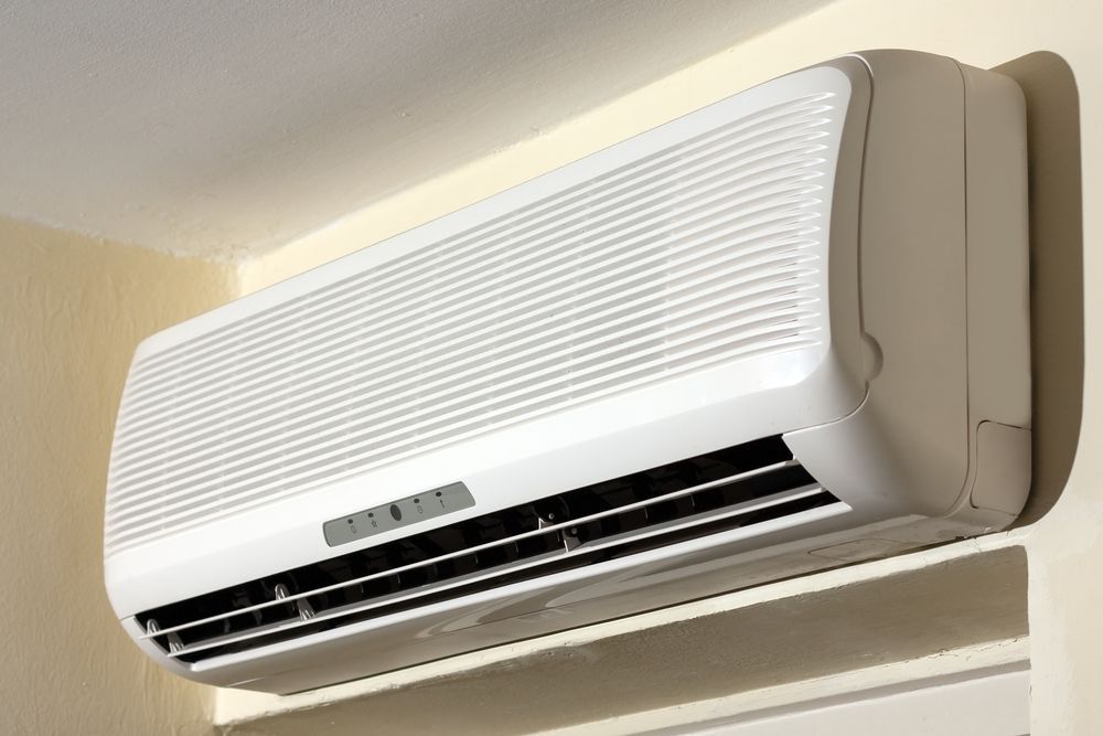 White Wall-mounted Air Conditioner on a Beige Wall, Casting a Shadow — RedJak Air Conditioning Services in Underwood, QLD