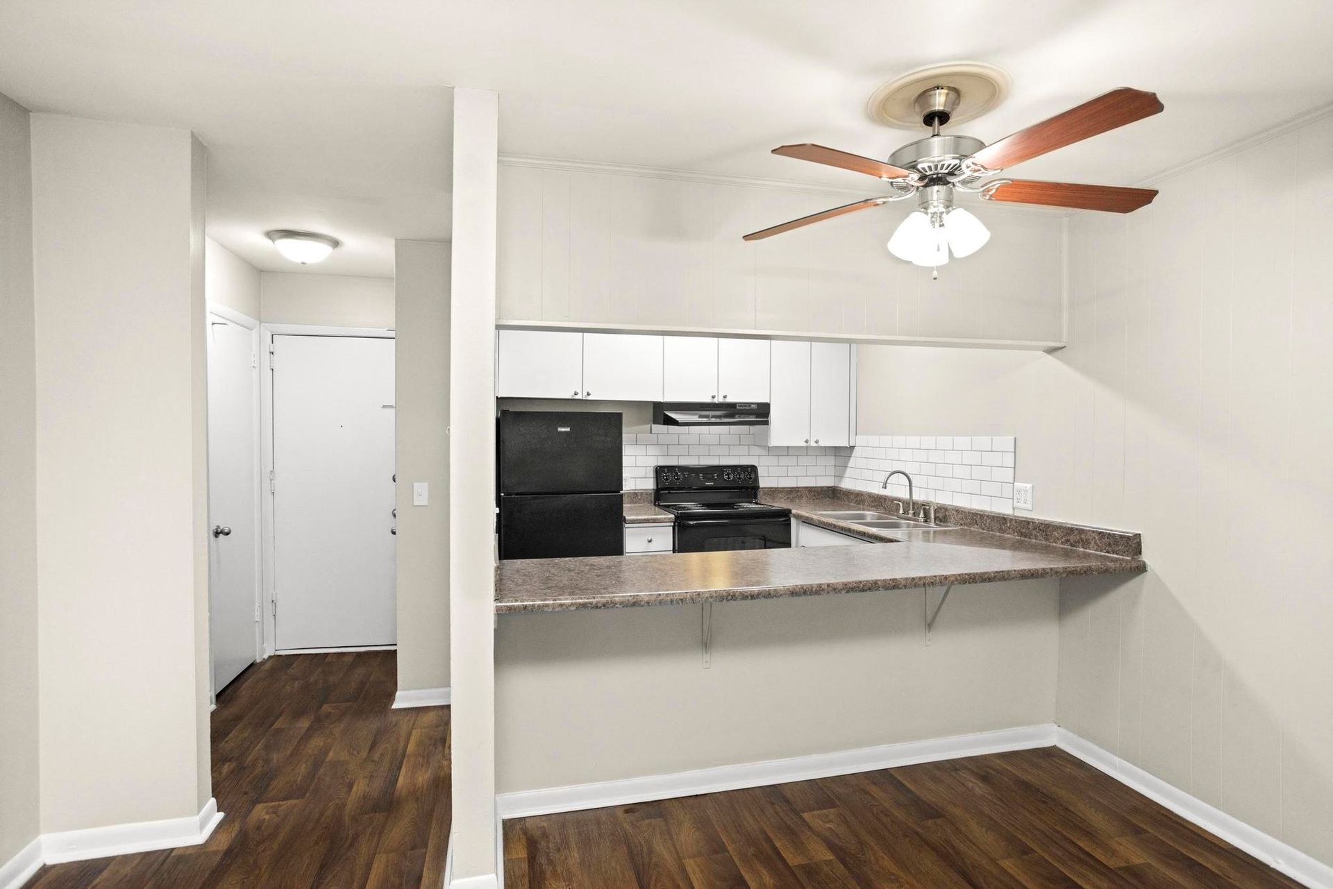 Small kitchen and dining area with white cabinets, black appliances, granite counter, and wood floors.