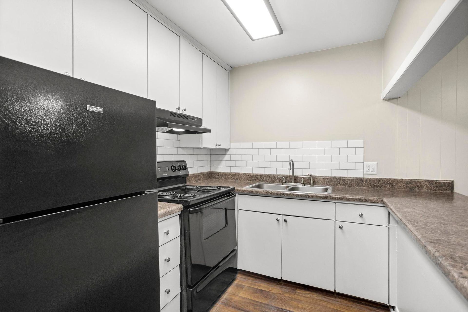 Small modern kitchen with black appliances, white cabinets, and gray countertops