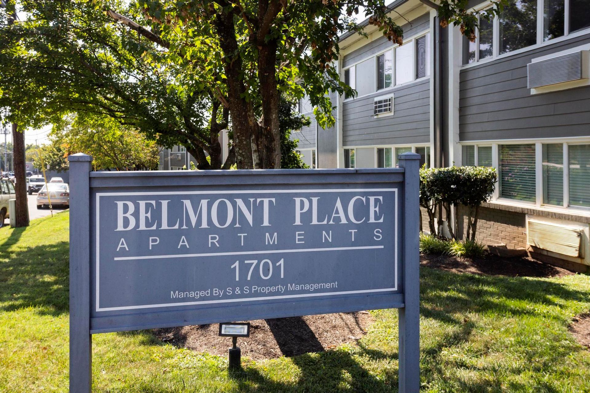 Belmont Place Apartments sign in front of a building and trees on a sunny day