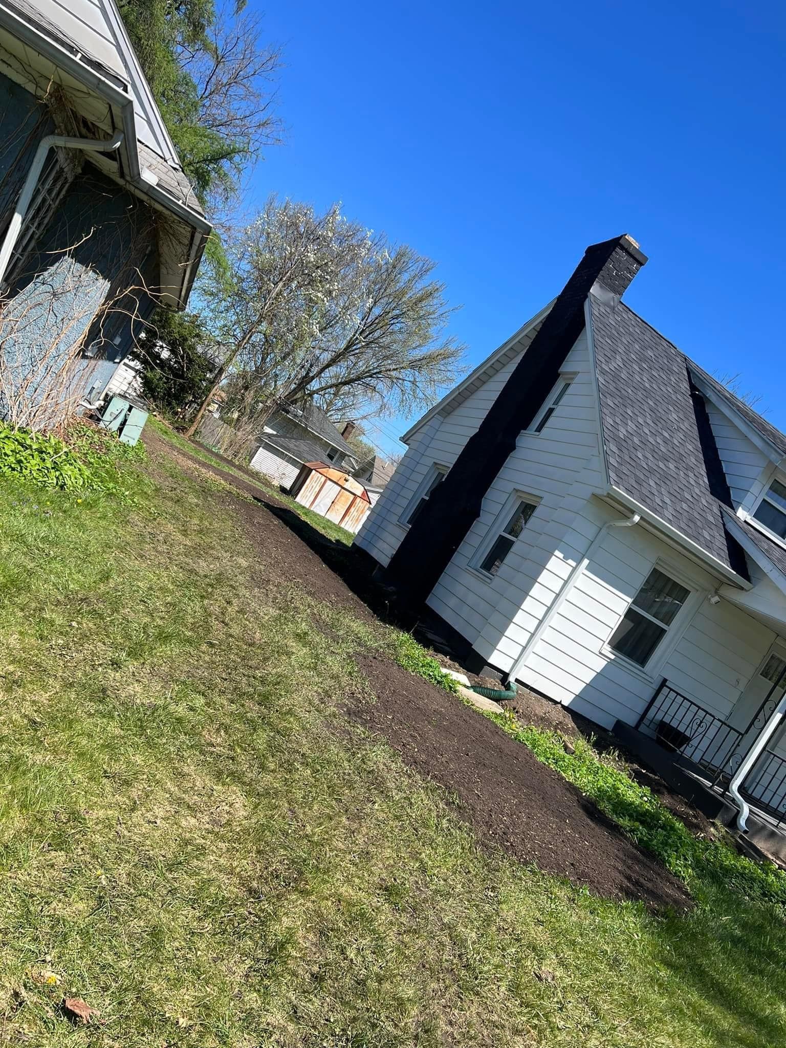 A white house with a black chimney in the backyard.
