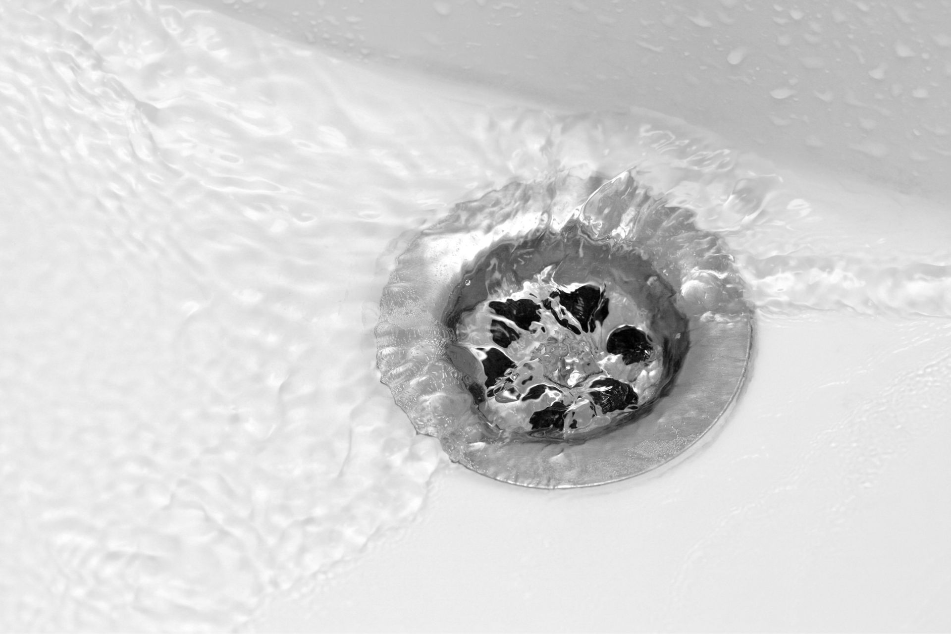 A close up of a sink drain with water running down it.