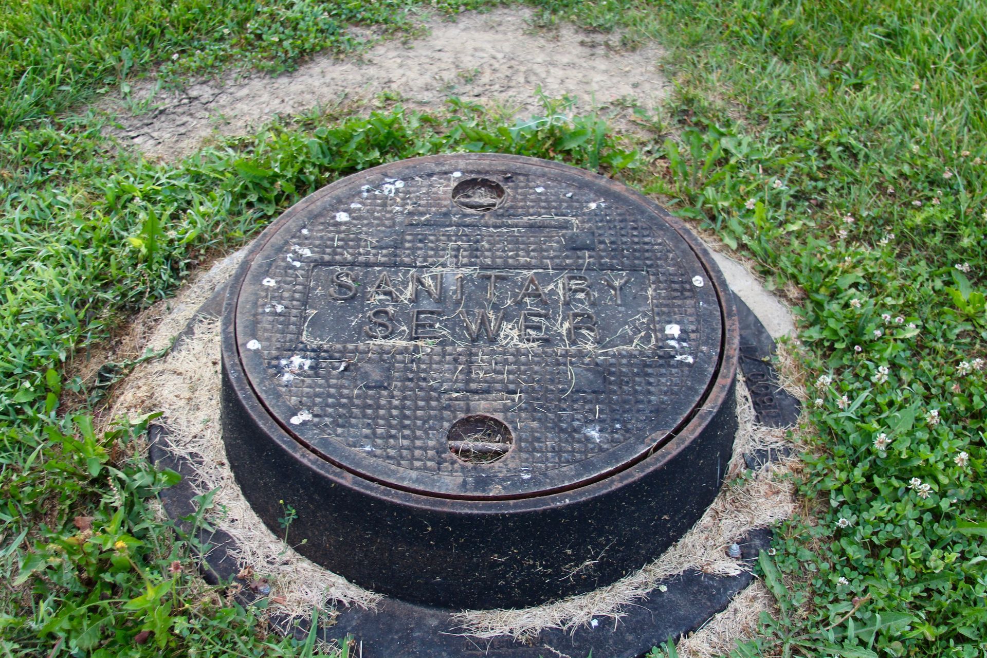A manhole cover is sitting in the middle of a grassy field.