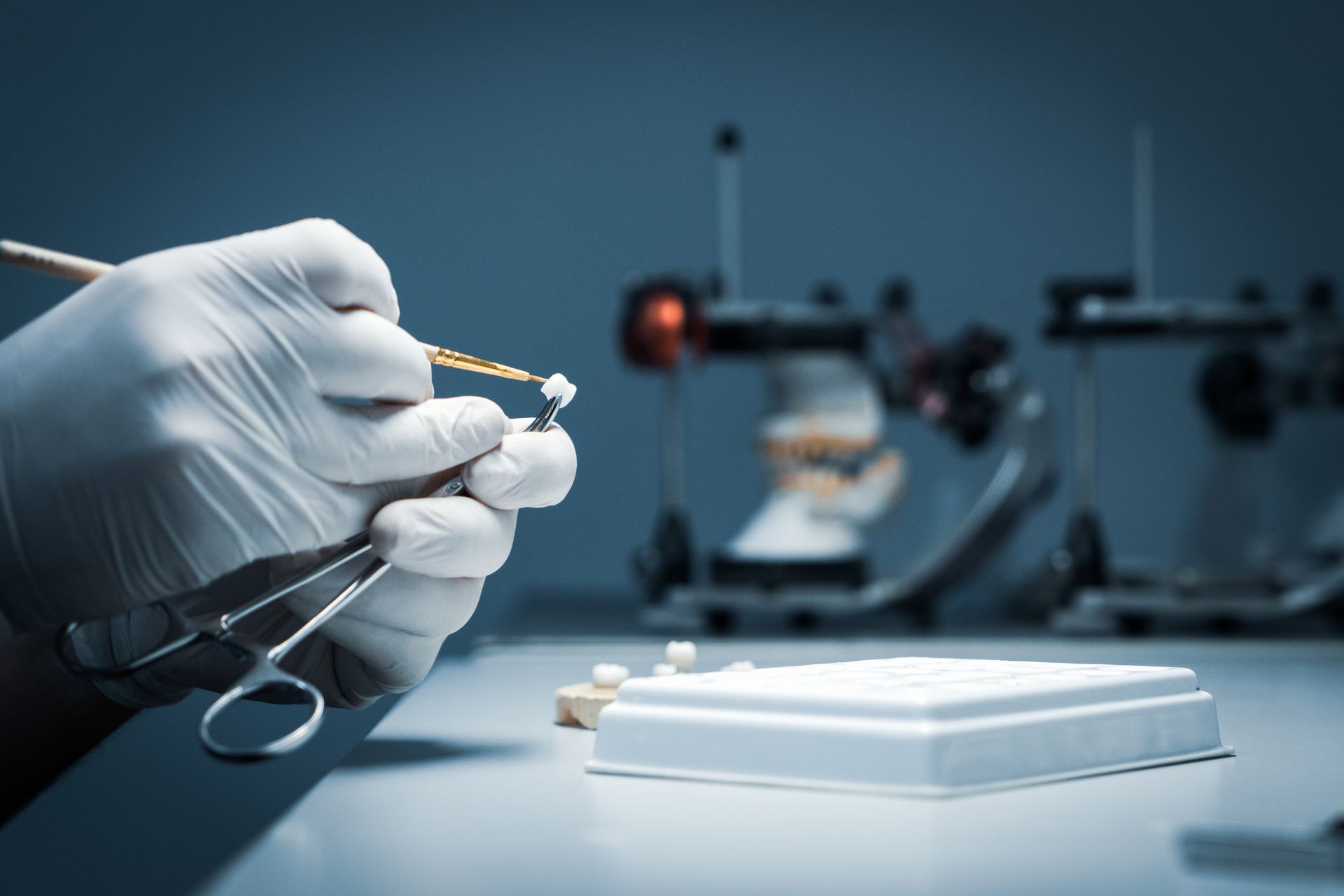 Technician inspecting a zirconia implant crown at a dental implants lab. Technician inspecting a zirconia implant crown at a dental implants lab.