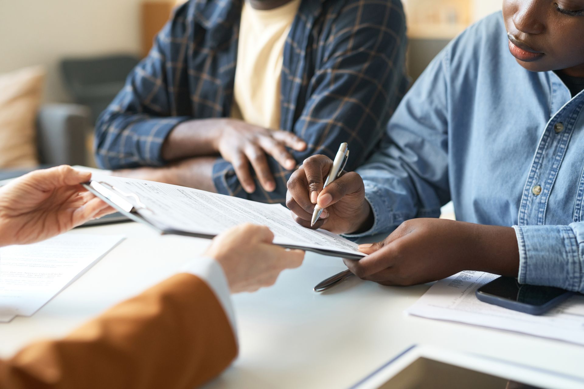 People reviewing documents at a table, with hands pointing and writing during a meeting
