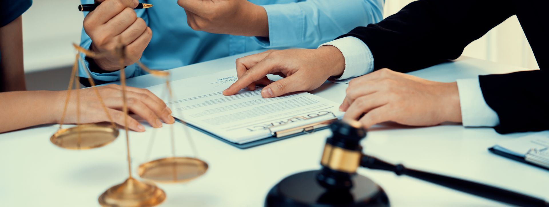 Hands using a keyboard and legal gavel on a desk, suggesting a business meeting or courtroom discussion