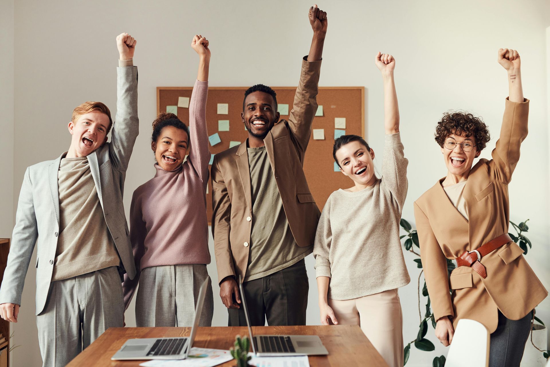 Five people smiling and raising their left fists in the air