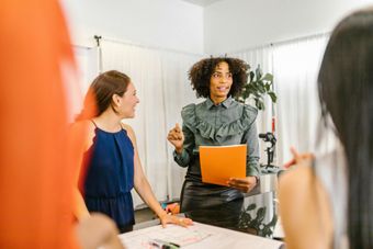 Women brainstorming and discussing ideas in a meeting, representing the creative and collaborative environment at Luxe Cosmetic Studios.