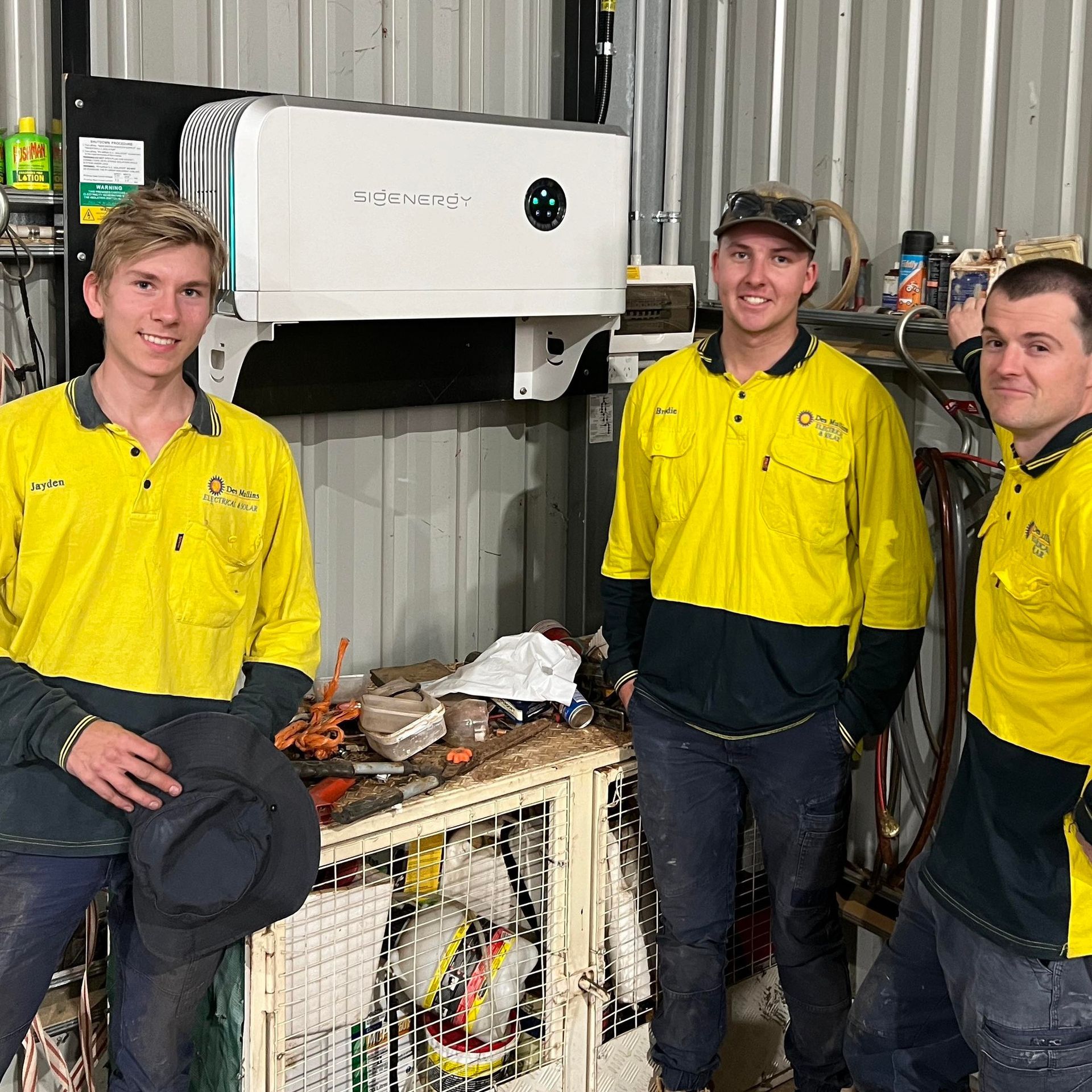 Three Workers in Yellow Shirts Stand in a Workshop — Des Mullins Electrical & Solar in Wagga Wagga, NSW
