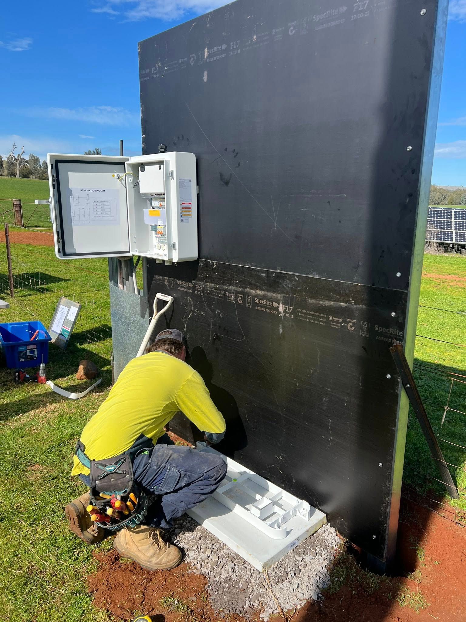 A Person in Work Clothes Installs Electrical Components — Des Mullins Electrical & Solar in Wagga Wagga, NSW