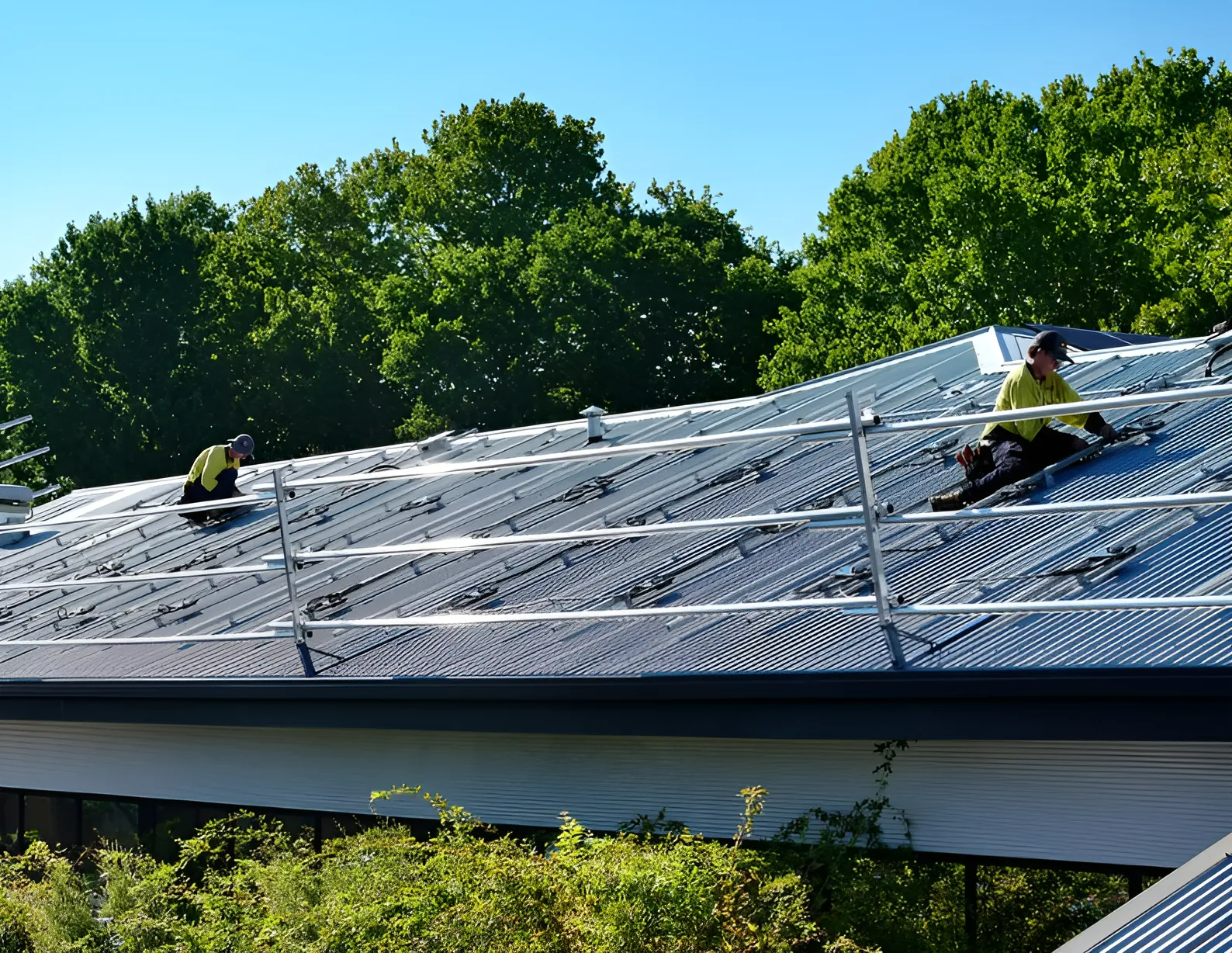 Two Workers in Yellow Shirts Repair a Corrugated Metal Roof — Des Mullins Electrical & Solar in Wagga Wagga, NSW