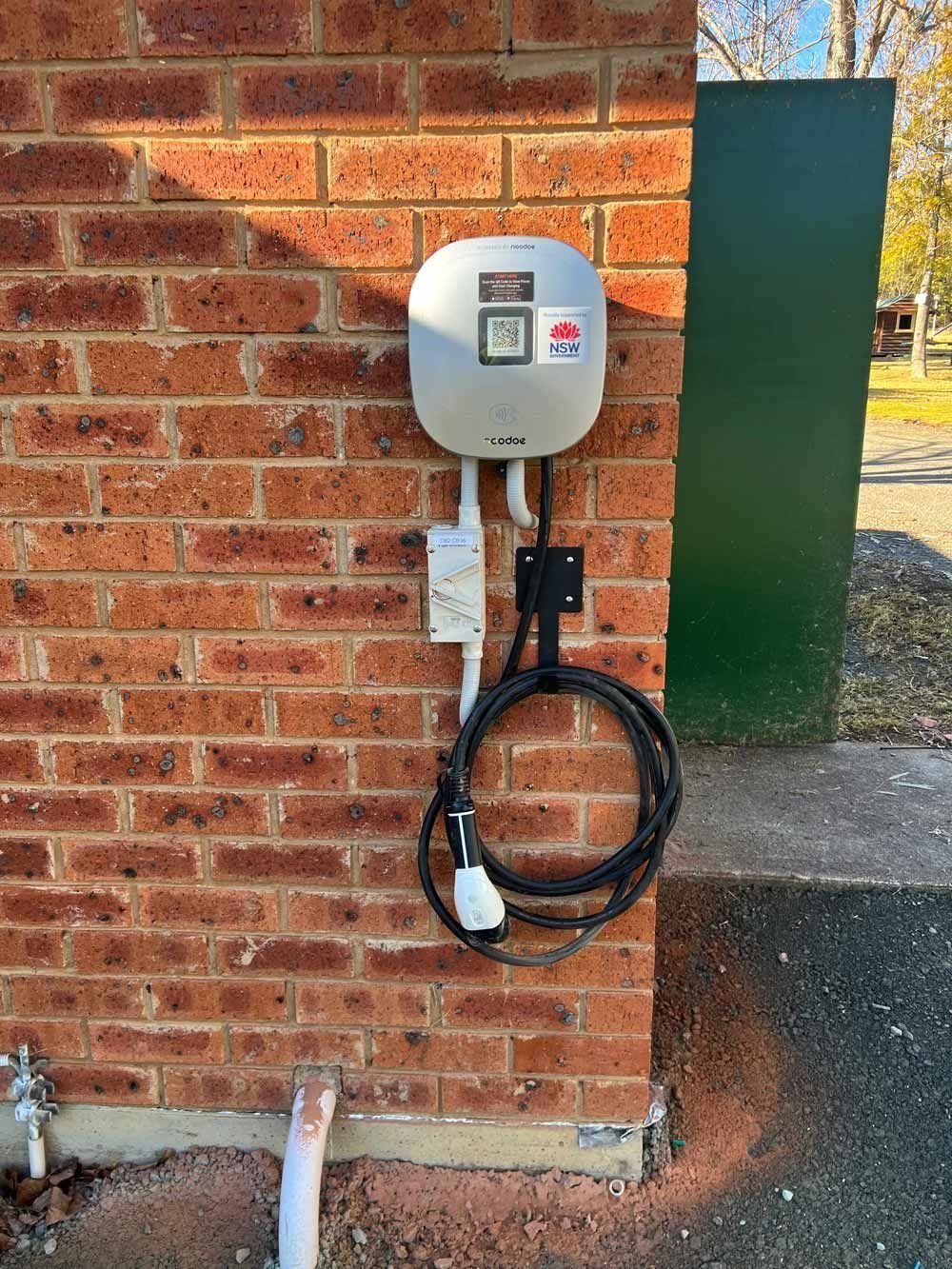 Electric Vehicle Charger on a Brick Wall — Des Mullins Electrical & Solar in Wagga Wagga, NSW Electric Vehicle Charger on a Brick Wall — Des Mullins Electrical & Solar in Wagga Wagga, NSW
