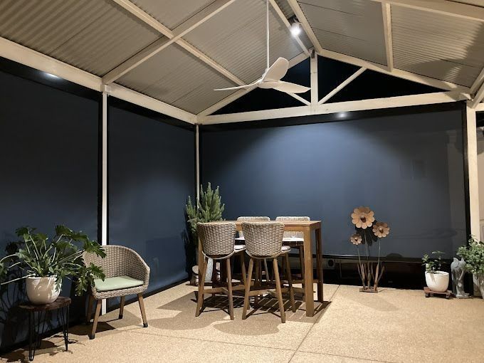 Outdoor Patio With a Table, Chairs, and Dark Blue Blinds — Des Mullins Electrical & Solar in Wagga Wagga, NSW