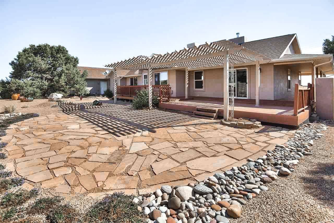 Single-story house with stone patio and landscaped front yard under a bright sky