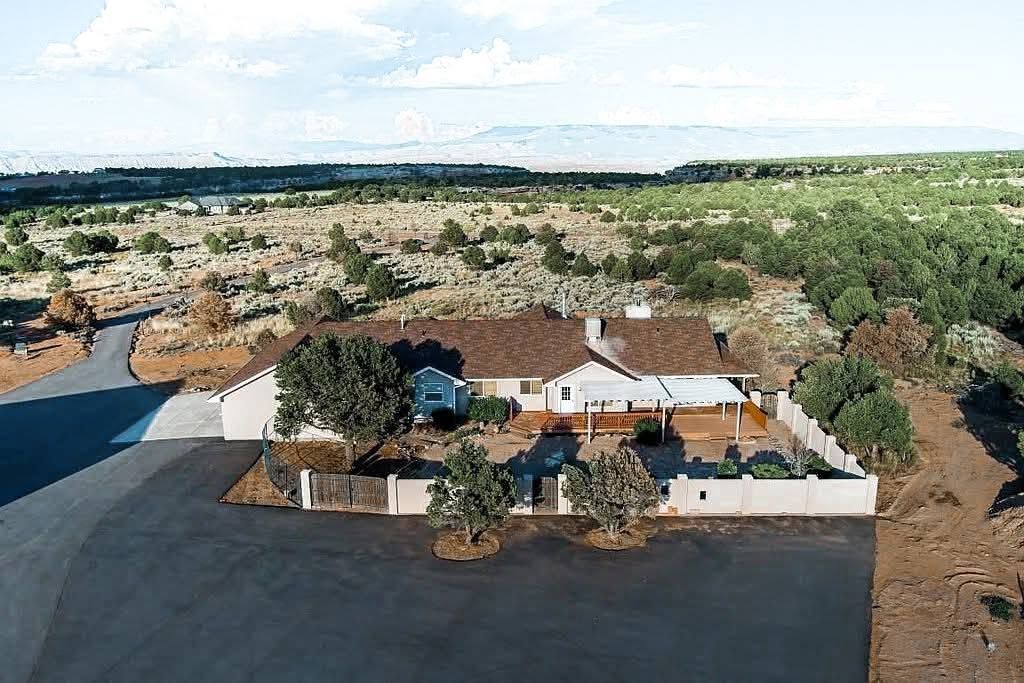 Aerial view of a white-walled house with a red roof in a dry, rural landscape.